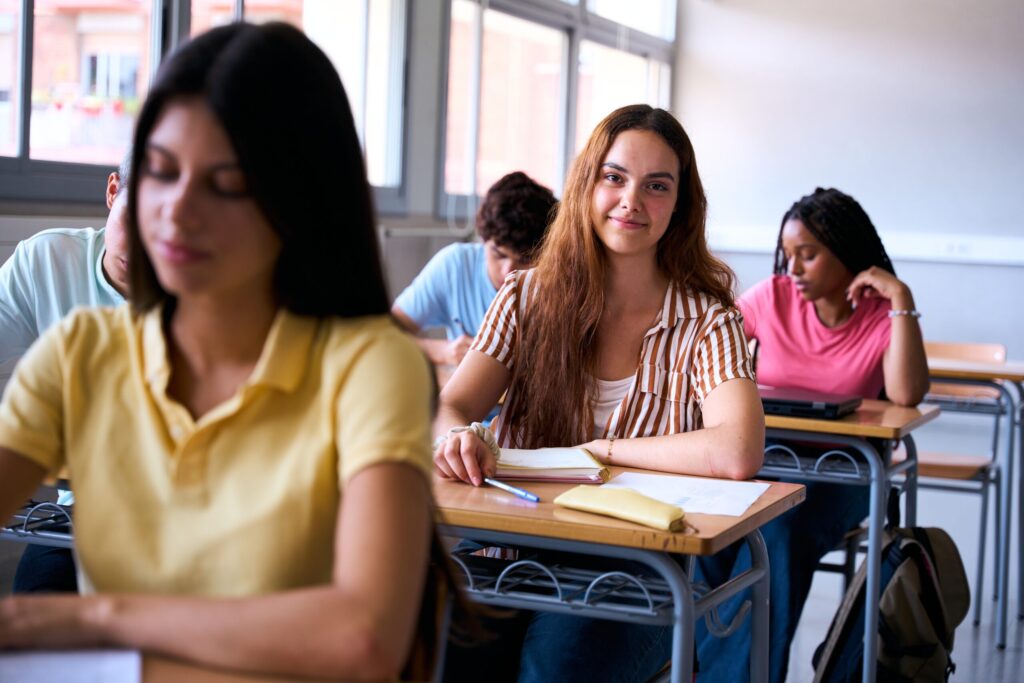 Why On-Site English Learning Works Better 1 Students practising on-site English learning in a bright classroom setting, focusing during a lesson designed to build confidence and fluency.